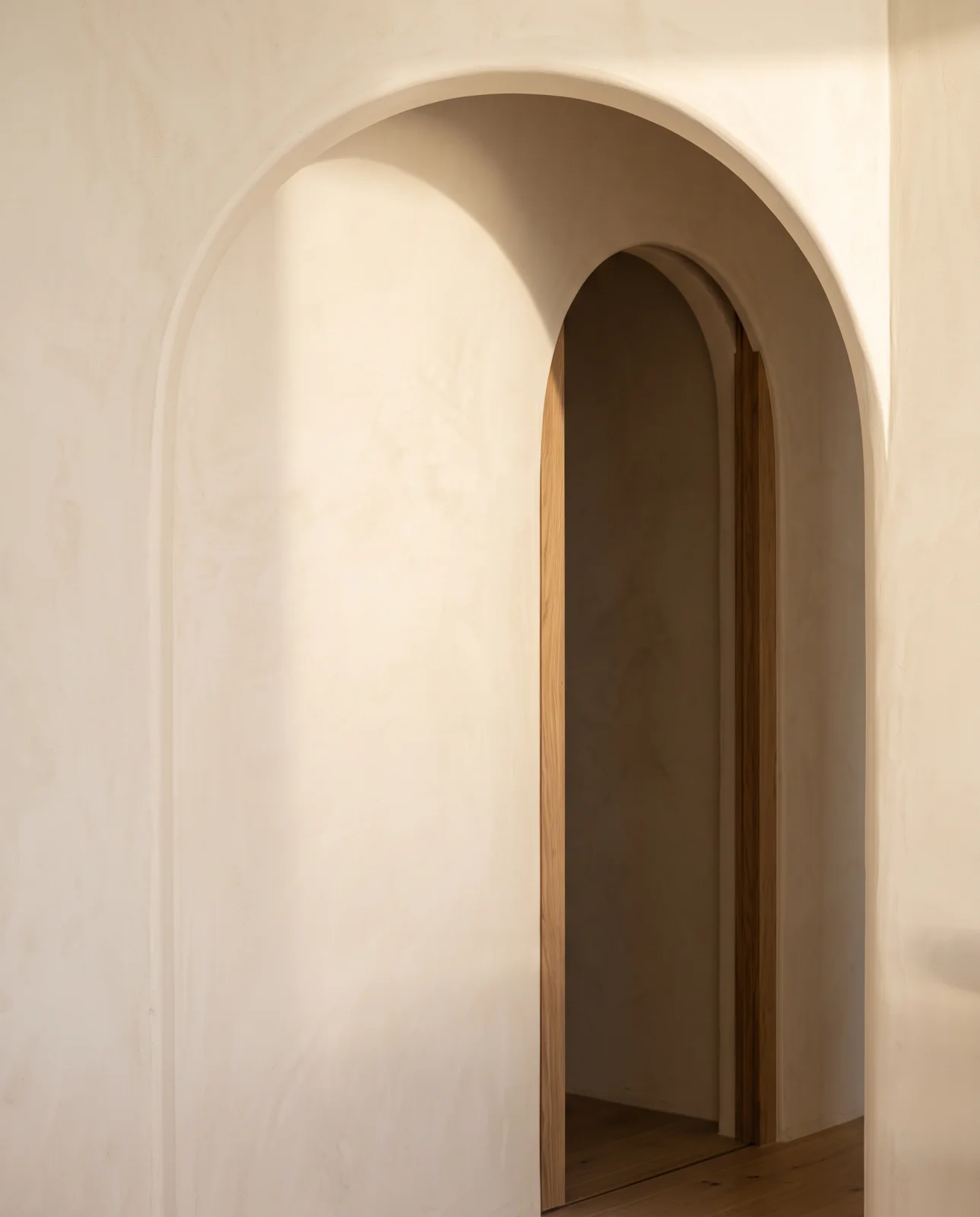 Close detail of a rounded ivory plaster archway with natural light